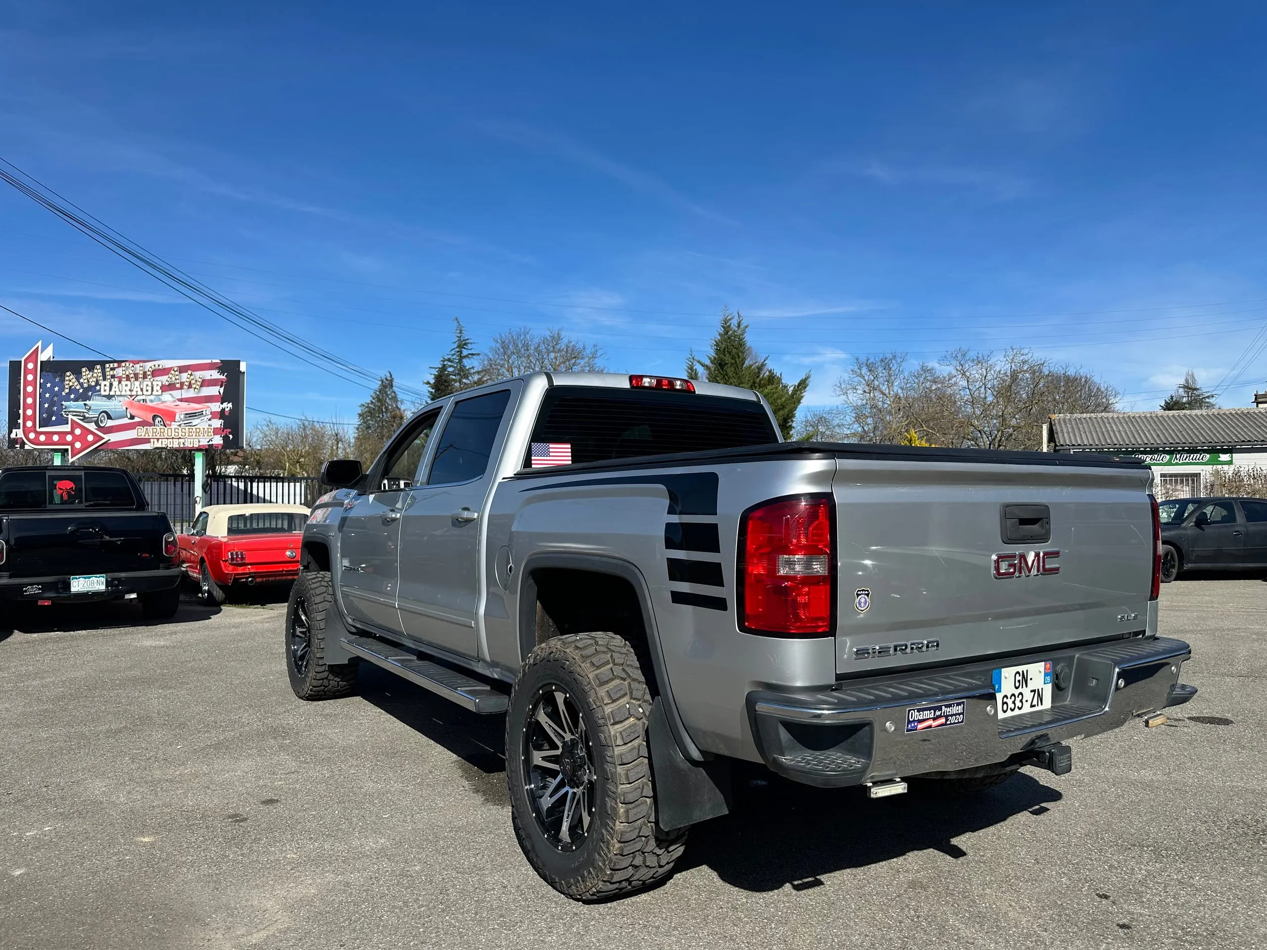 GMC Sierra Denali Crew Cab gris argent vu de trois quarts arrière avec son couvre-benne