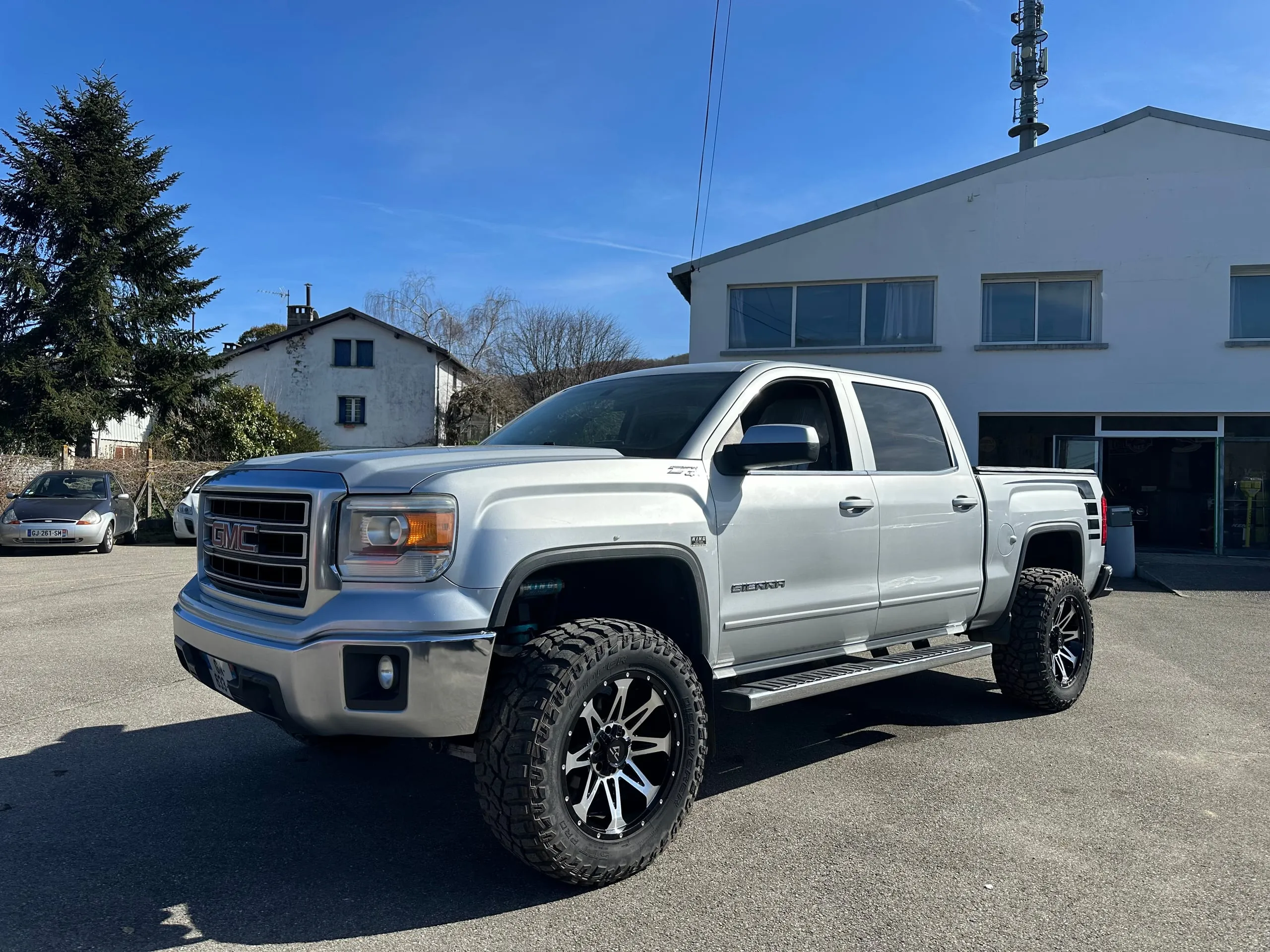 GMC Sierra Denali Crew Cab gris argent surélevé, photographié de trois quarts avant