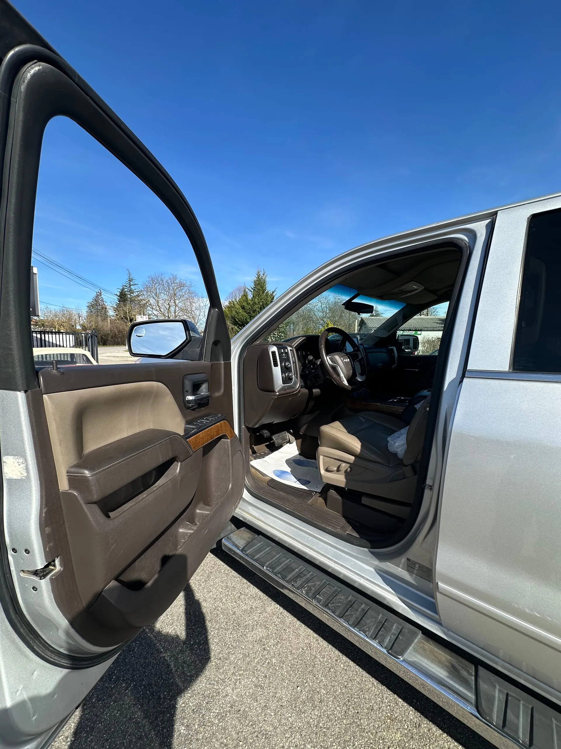 Habitacle avant en cuir brun du GMC Sierra Denali, porte conducteur ouverte
